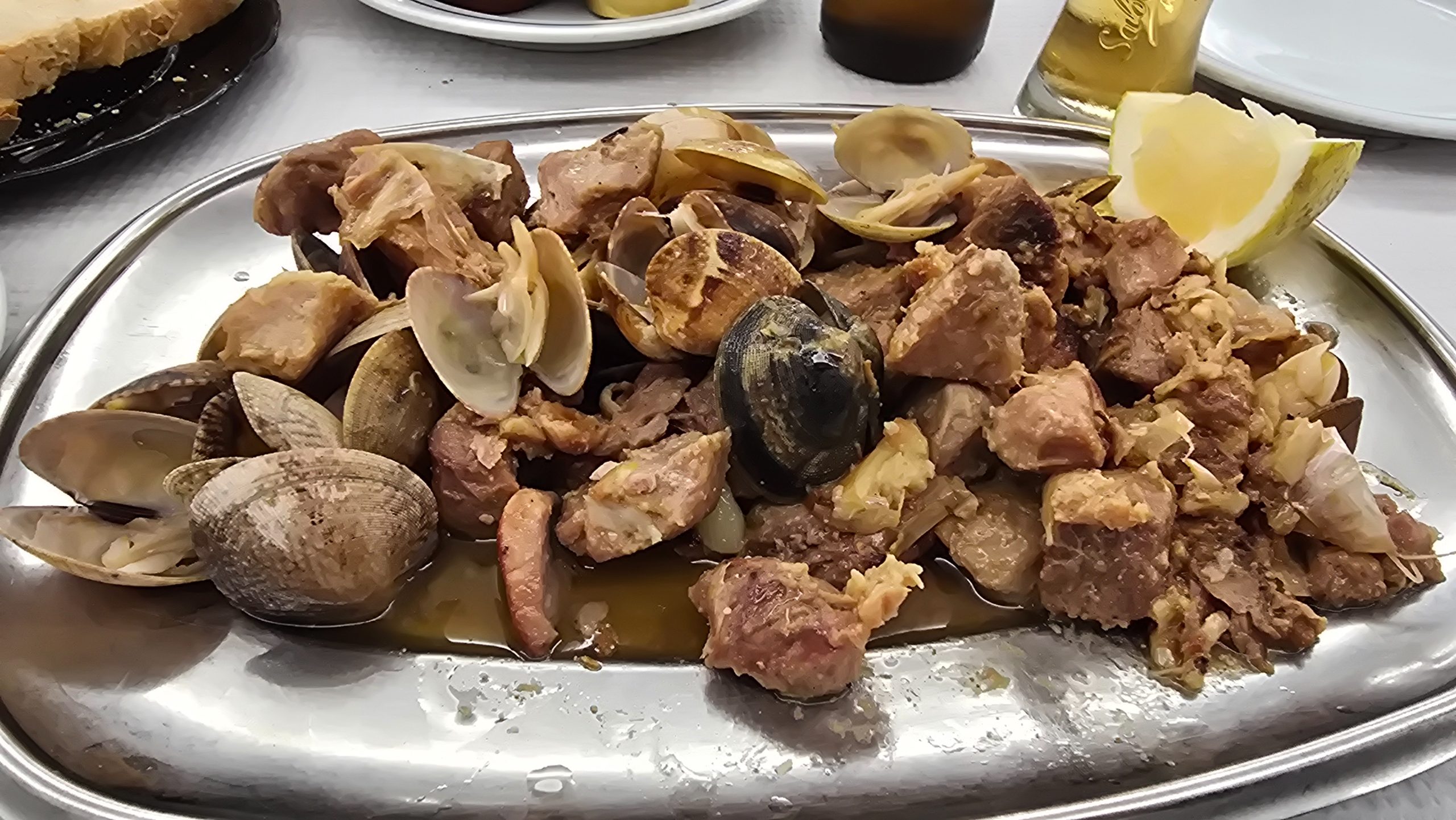 Jantando no primo dos caracóis uma carne de porco com amêijoas